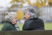 Happy senior couple sharing headphones, listening to music in park — Stock Photo