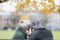 Couple de personnes âgées partageant des écouteurs, écoutant de la musique dans le parc d'automne — Photo de stock