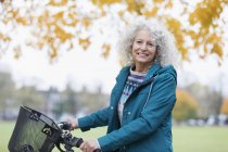 Porträt selbstbewusste, lächelnde Seniorin radelt im Herbstpark — Stockfoto