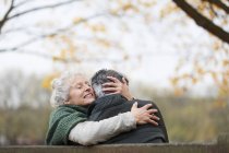 Ласковая, нежная пожилая пара обнимается в осеннем парке — стоковое фото
