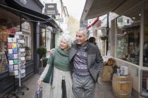 Senioren-Paar geht in Gasse einkaufen — Stockfoto