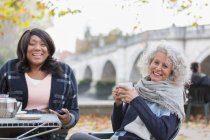 Портрет усміхнені, щасливі активні старші жінки друзі п'ють каву в кафе осіннього парку — стокове фото