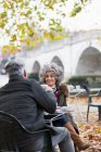 Smiling active senior couple enjoying coffee at autumn park cafe — Stock Photo