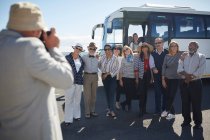 Активні старші туристичні друзі позують для фотографії поза туристичним автобусом — стокове фото