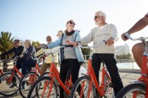 Amici turistici anziani attivi in bicicletta sul lungomare soleggiato — Foto stock