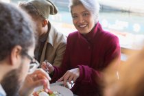 Retrato sonriente mujer joven comiendo con amigos en el restaurante - foto de stock