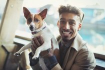 Retrato sonriente joven sosteniendo perro - foto de stock