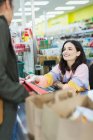 Caixa de supermercado ajudando o cliente no checkout — Fotografia de Stock