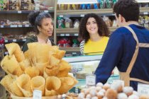 Frauen unterhalten sich mit Arbeiterin an der Vitrine einer Bäckerei im Supermarkt — Stockfoto
