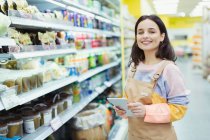 Portrait confident, smiling female grocer with digital tablet in supermarket — Stock Photo