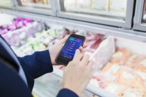Frau nutzt Einkaufslisten-App, kauft im Supermarkt ein — Stockfoto