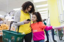 Mutter und Tochter mit Smartphone im Supermarkt einkaufen — Stockfoto