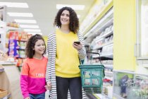 Посміхаючись мати і дочка купують в супермаркеті — стокове фото