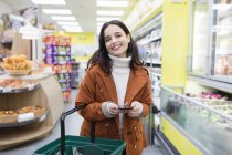 Портрет улыбается, уверенная женщина со смартфоном покупки в супермаркете — стоковое фото