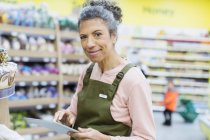 Улыбающийся портрет, уверенная бакалейщица с цифровым планшетом, работающая в супермаркете — стоковое фото