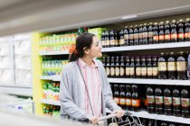 Mujer sonriente de compras en el supermercado - foto de stock