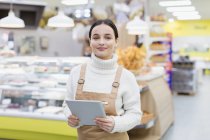Porträt selbstbewusste Lebensmittelhändlerin mit digitalem Tablet im Supermarkt — Stockfoto