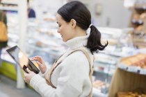 Merceeiro feminino com tablet digital trabalhando no supermercado — Fotografia de Stock