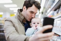 Прихильний батько і дитина дочка беруть селфі в супермаркеті — стокове фото