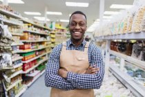Retrato seguro, sonriente tendero masculino trabajando en el supermercado - foto de stock