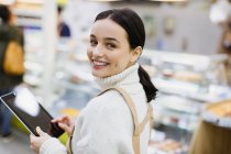 Portrait souriant, confiant épicier féminin avec tablette numérique travaillant dans les supermarchés — Photo de stock