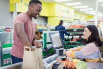 Kassiererin hilft Kundin an Supermarktkasse — Stockfoto