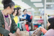 Cashier helping customer at supermarket checkout — Stock Photo