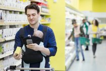 Pai com rótulo de digitalização do bebê na caixa no supermercado — Fotografia de Stock