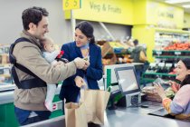 Young family at supermarket checkout — Stock Photo
