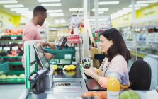 Kassiererin hilft Kundin an Supermarktkasse — Stockfoto