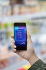 Frau aus persönlicher Perspektive betrachtet digitale Einkaufsliste auf Smartphone im Supermarkt — Stockfoto