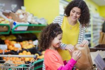 Mother and daughter shopping for produce in supermarket — Stock Photo