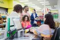 Cashier helping customers at supermarket checkout — Stock Photo