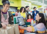 Cassiere aiutare i clienti alla cassa del supermercato — Foto stock