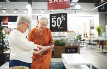 Seniorinnen mit digitalem Tablet shoppen im Einrichtungshaus — Stockfoto