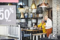 Старші жінки купують, дивлячись на тканинні годинники в магазині домашнього декору — стокове фото