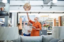 Старші жінки з цифровим планшетом дивиться на підвісне світло в магазині домашнього декору — стокове фото