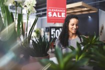 Femme souriante faisant des achats pour les plantes dans le magasin de décoration à la maison — Photo de stock