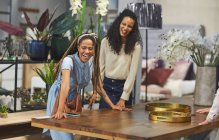 Happy women shopping for dining table in home decor shop — Stock Photo