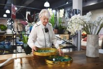 Mujer mayor mirando bandejas en la tienda de decoración del hogar - foto de stock