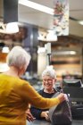 Дружня старша жінка-касир, яка допомагає клієнтам орендувати супермаркет — стокове фото