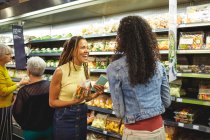 Heureuses femmes amis épicerie achats dans la section des produits du supermarché — Photo de stock