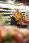 Mulheres sênior com compras de supermercado de telefone inteligente — Fotografia de Stock