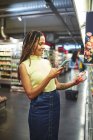 Donna sorridente con smart phone spesa al supermercato — Foto stock