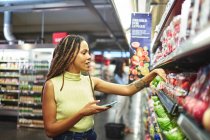 Женщина со смартфоном продуктовый магазин в супермаркете — стоковое фото