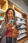 Lächelnde Frau mit Smartphone beim Einkauf im Haushaltswarengeschäft — Stockfoto