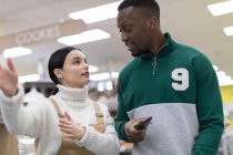 Mujer tendero ayudando a cliente masculino en el supermercado - foto de stock