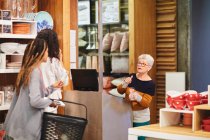 Seniorin hilft Frauen beim Einkaufen im Haushaltswarengeschäft — Stockfoto