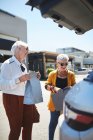 Щасливі старші жінки друзі завантажують сумки в позашляховик на парковці торгового центру — стокове фото
