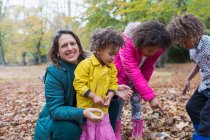 Retrato mãe feliz e crianças brincando em folhas de outono — Fotografia de Stock